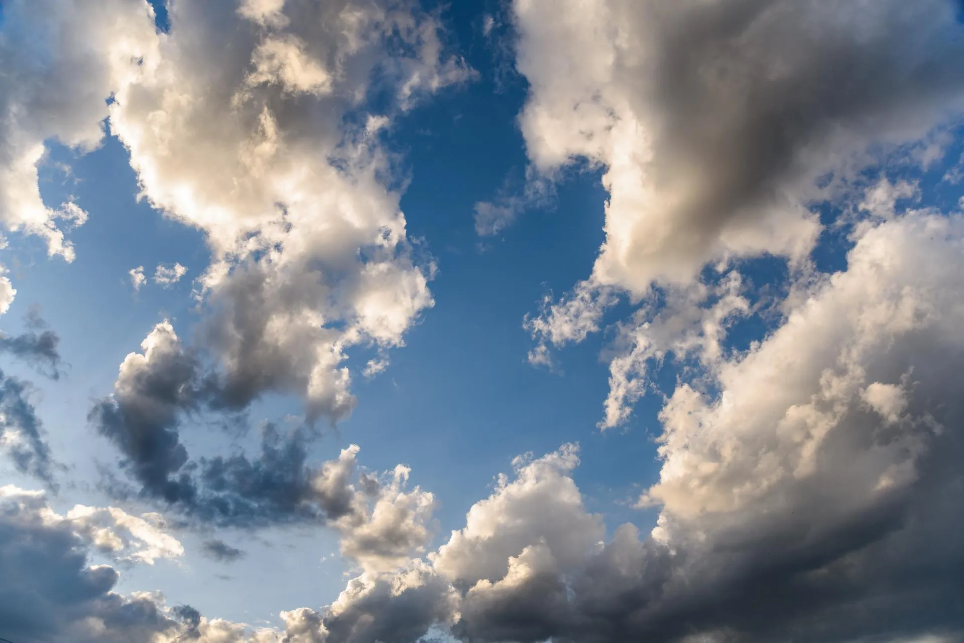 Blue sky with large, fluffy white and gray clouds scattered across it.