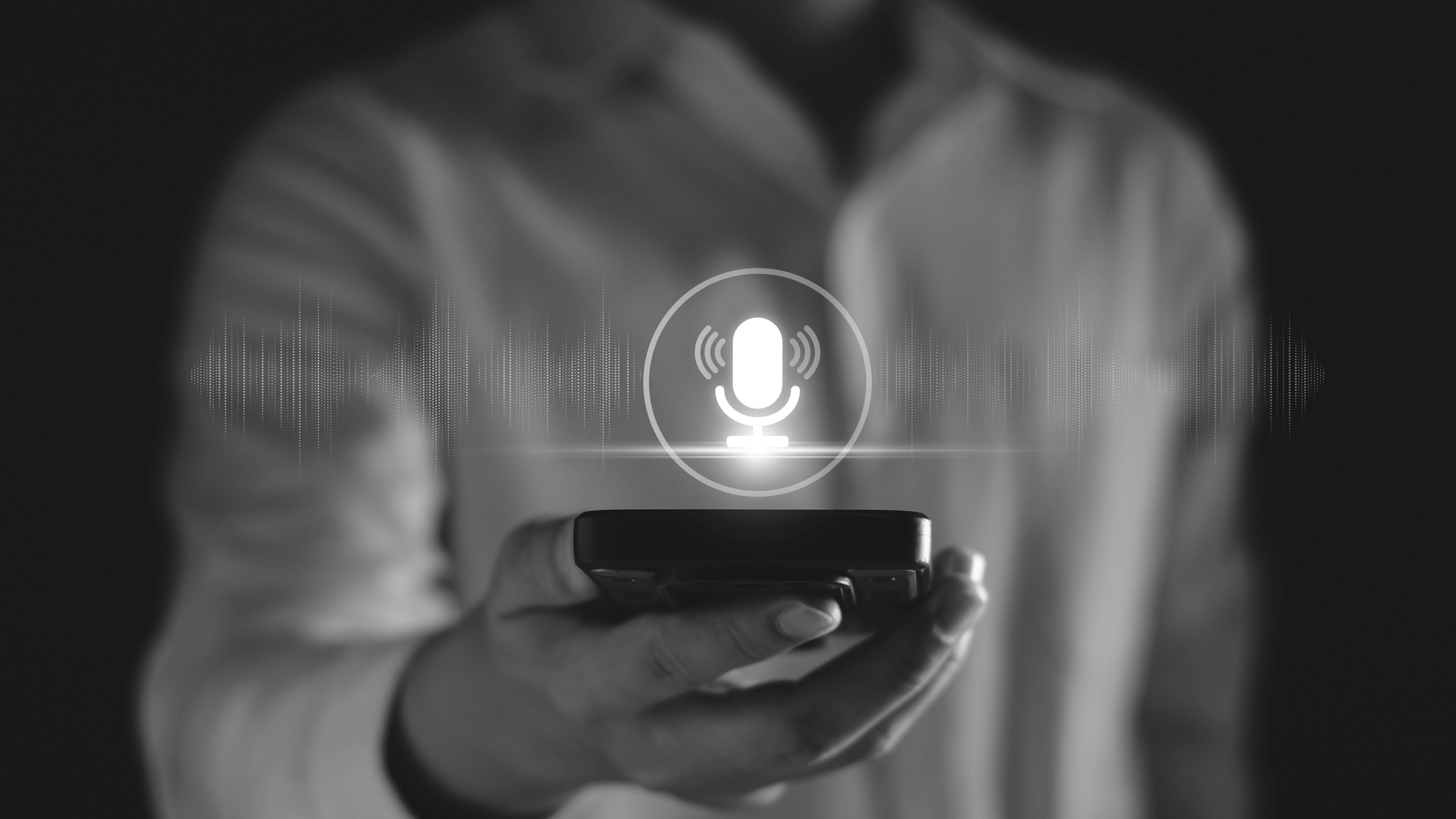 Man holding a phone with a graphic of a microphone indicating the man is talking to the phone and the phone is interpreting the speech