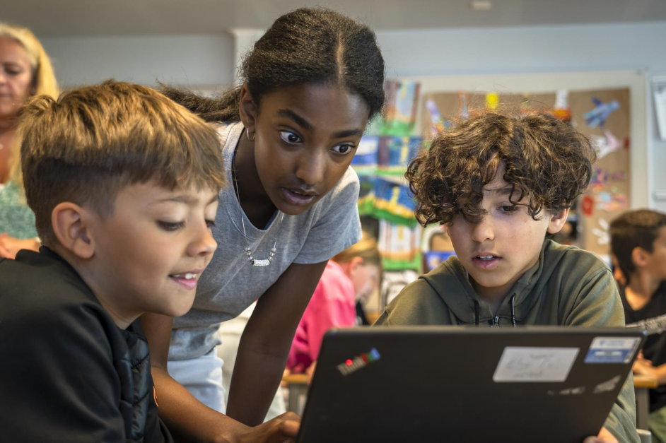 Tre elever som ser paa en pc-skjerm. De ser ivrige ut