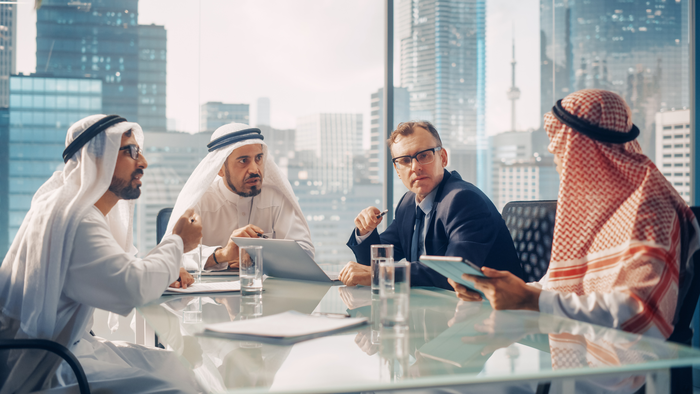 Business leaders in Saudi Arabia and international executives discussing opportunities in a modern office, reflecting Vision 2030 economic growth.