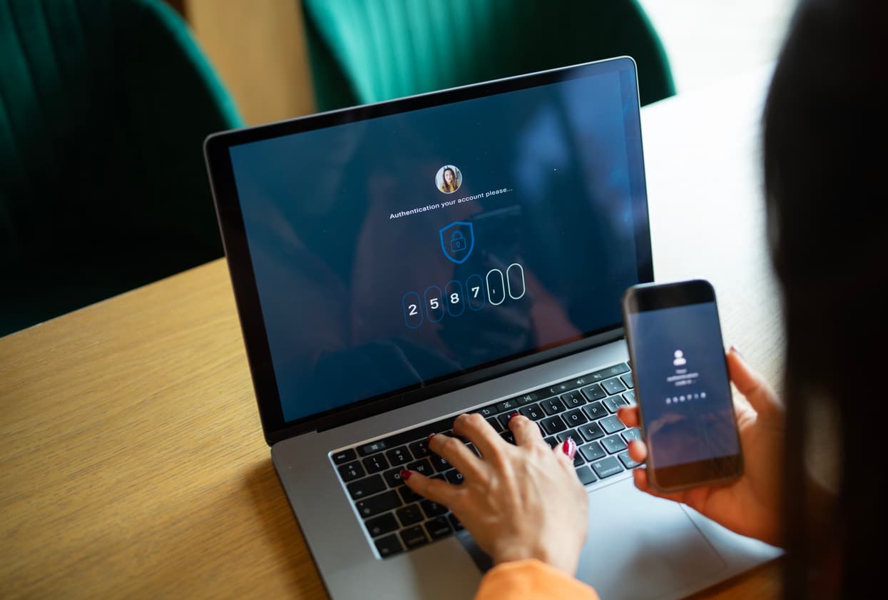 User completing multi-factor authentication on a laptop and mobile phone, representing the Home Office MFA rollout for Sponsor Management System users.