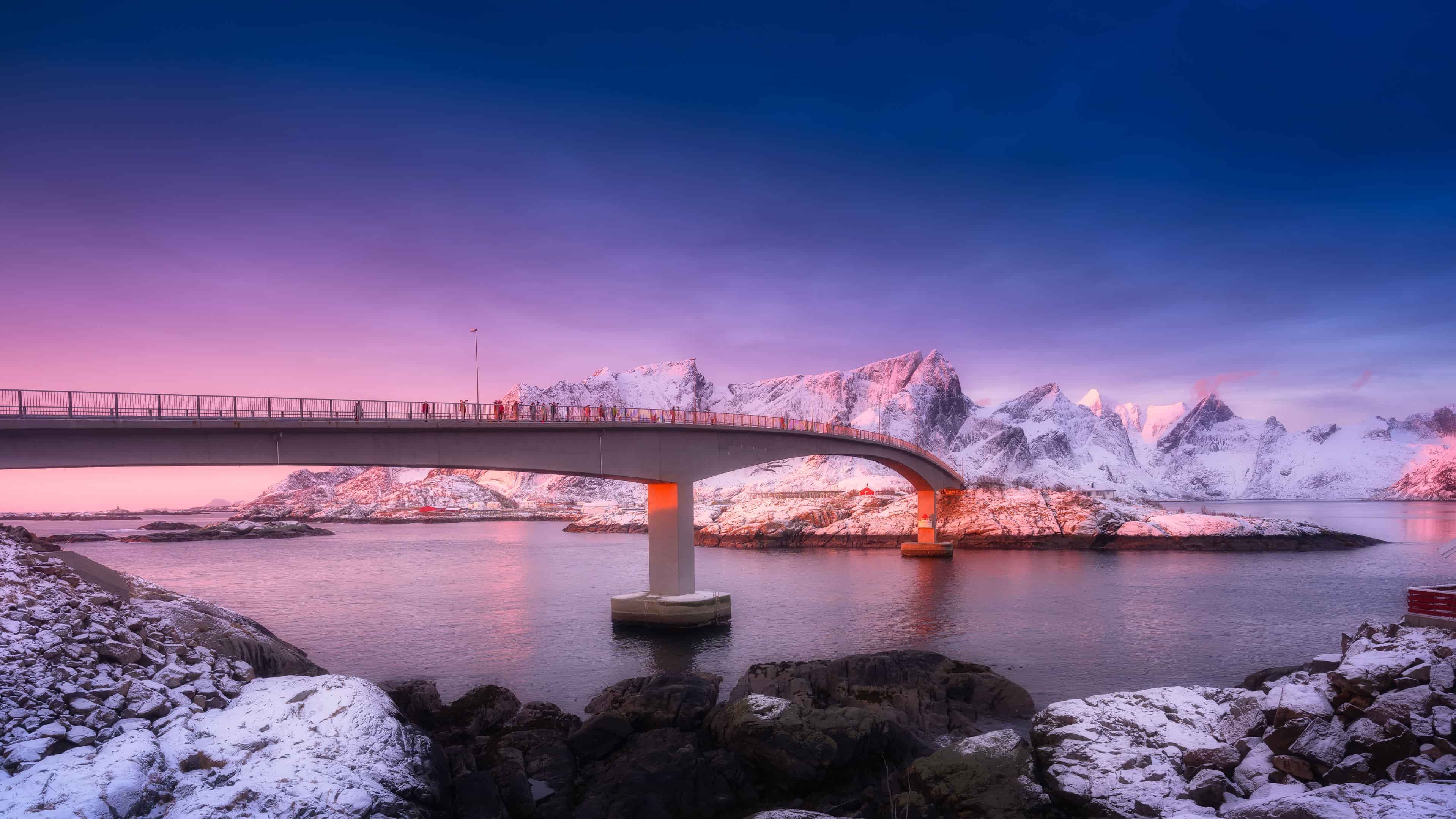 Snow-covered mountains and bridge in Norway at sunset