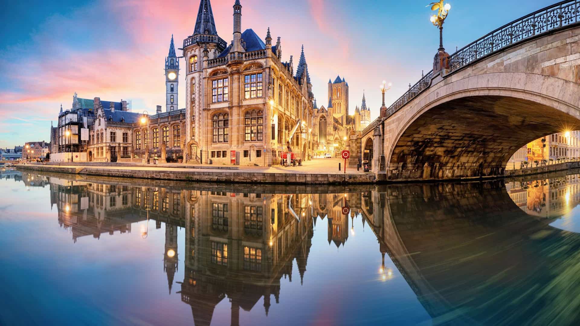 Historic buildings and bridge reflected in a canal in Belgium at sunset