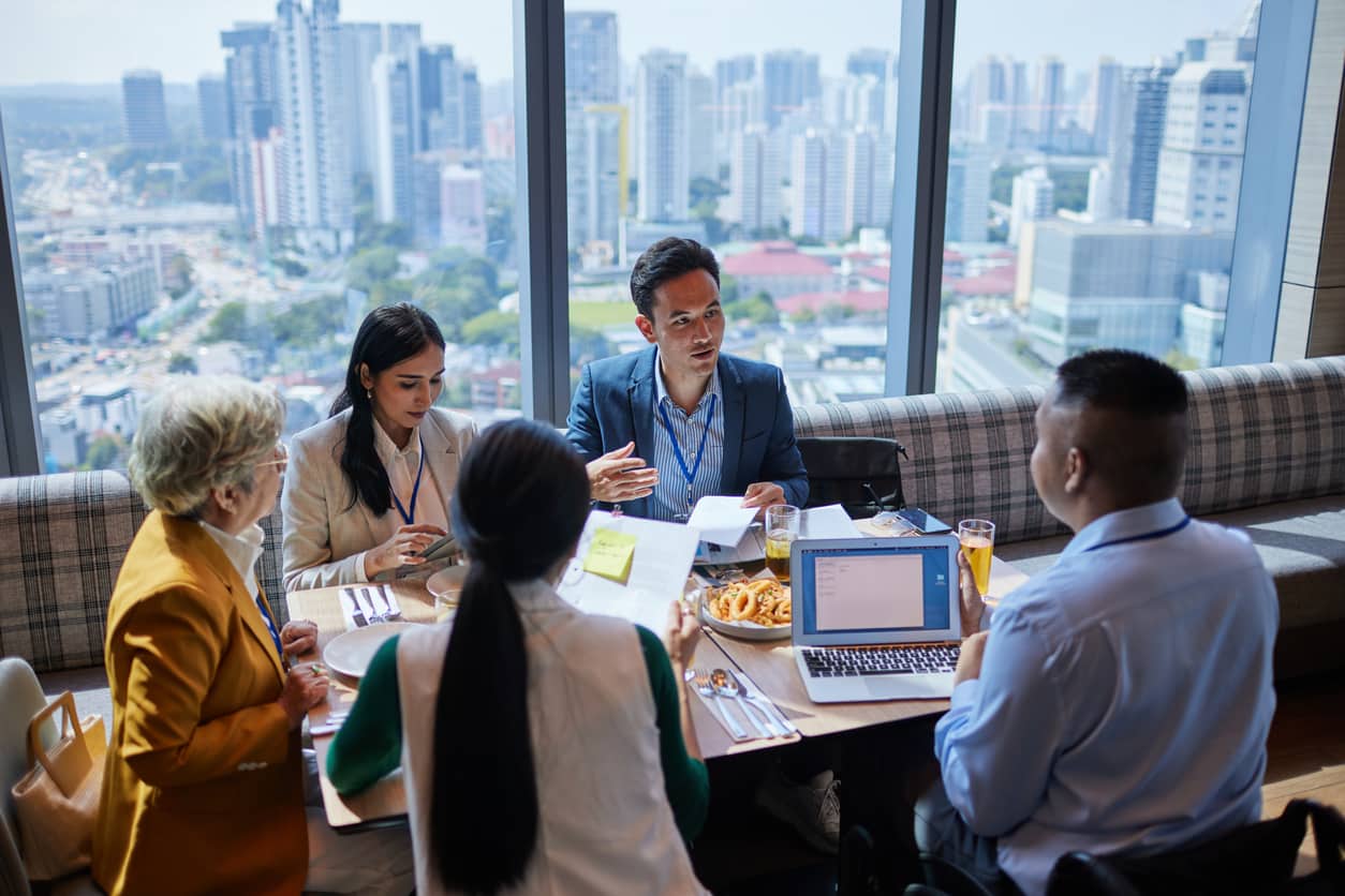 Business professionals in Singapore discussing Employment Pass and COMPASS salary requirements