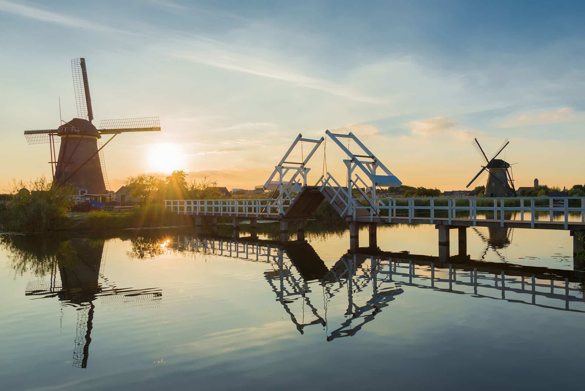 Traditional Dutch windmills and bridge beside water in the Netherlands at sunset