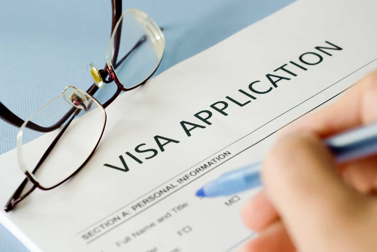 Visa application form with a calculator, pen and reading glasses, representing UK visa fees and fee waiver requests