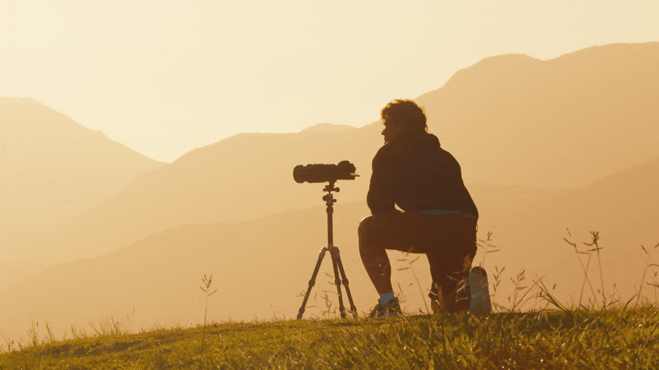 Man shooting video at sunset in the mountains