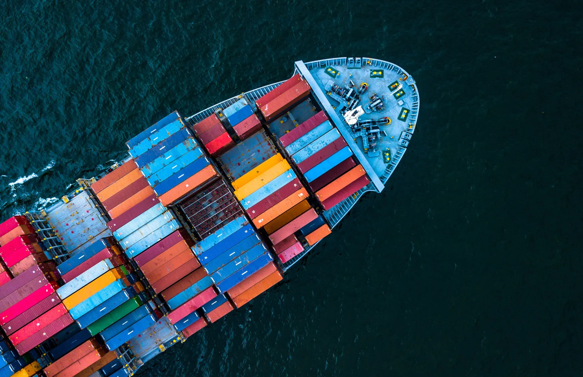 Aerial view of a large container ship carrying colorful shipping containers on the ocean.