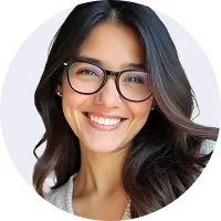 Smiling woman with long dark hair and glasses wearing a light-colored top, looking at the camera.