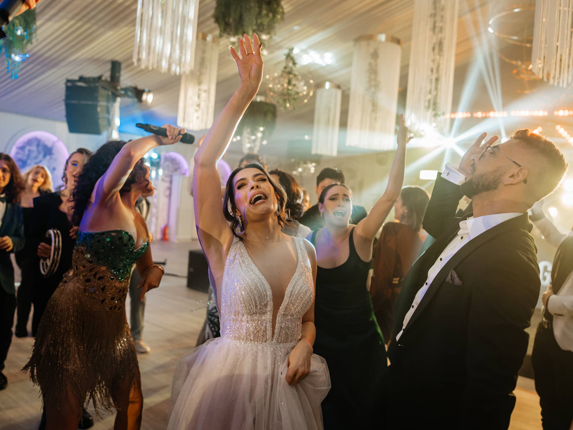 O mireasă și invitați dansează și cântă la o petrecere festivă înăuntru.