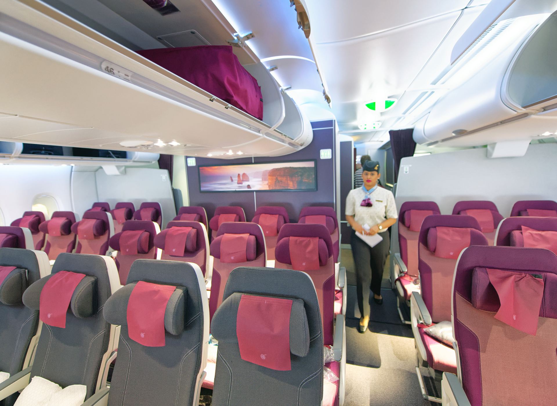 Modern aircraft economy cabin with flight attendant.