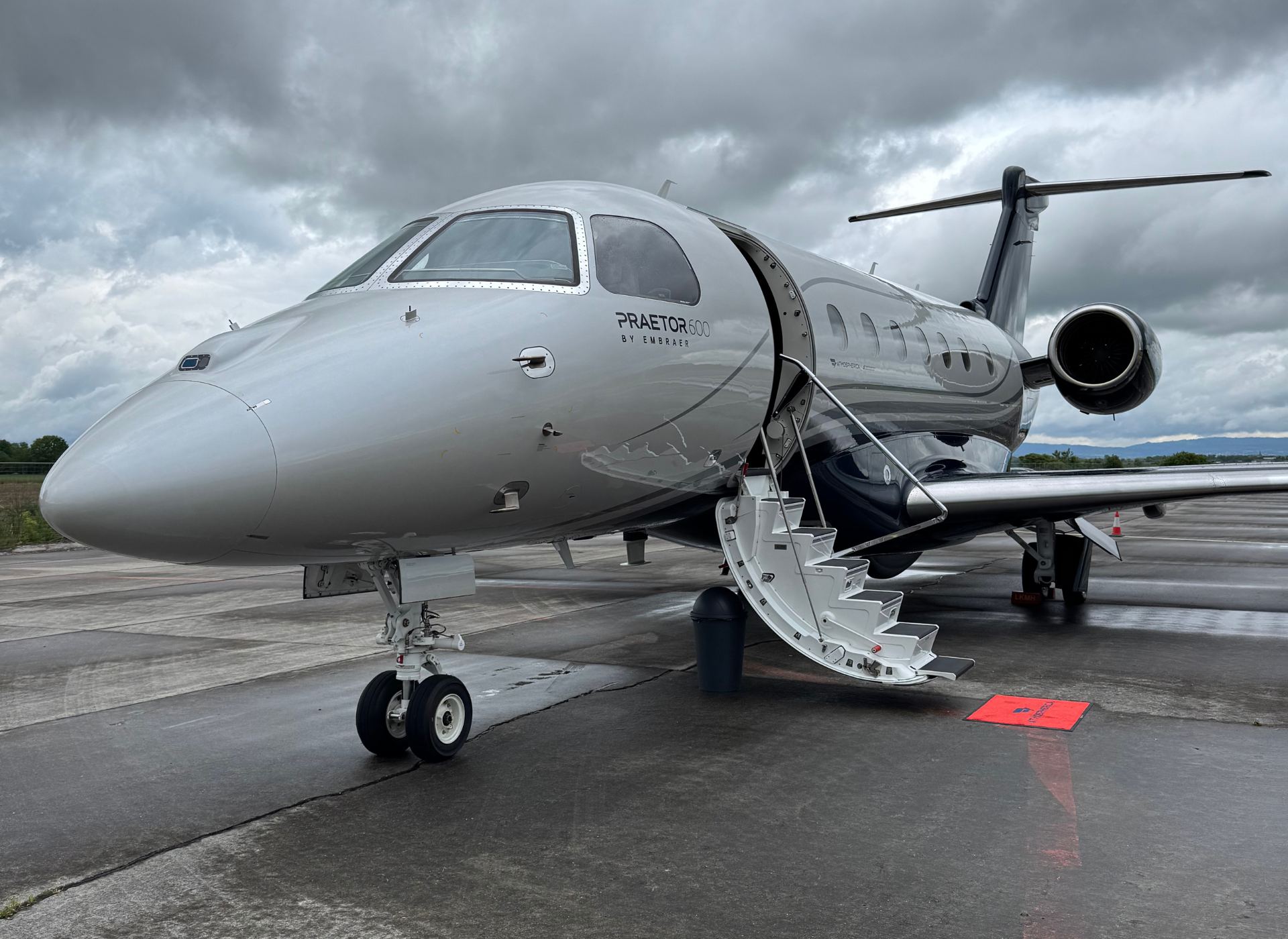 Jet privé Embraer Praetor 600 stationné sur le tarmac avec porte ouverte.