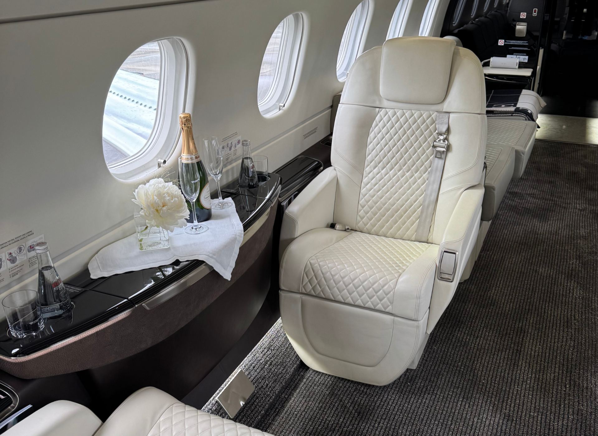 Cabine luxueuse d’un jet privé Embraer Praetor 600 avec champagne servi à bord.