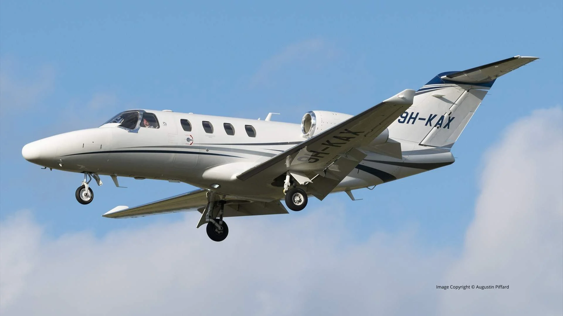 Jet privé léger Cessna Citation II en vol avec train d’atterrissage sorti, photographié sous un ciel bleu.