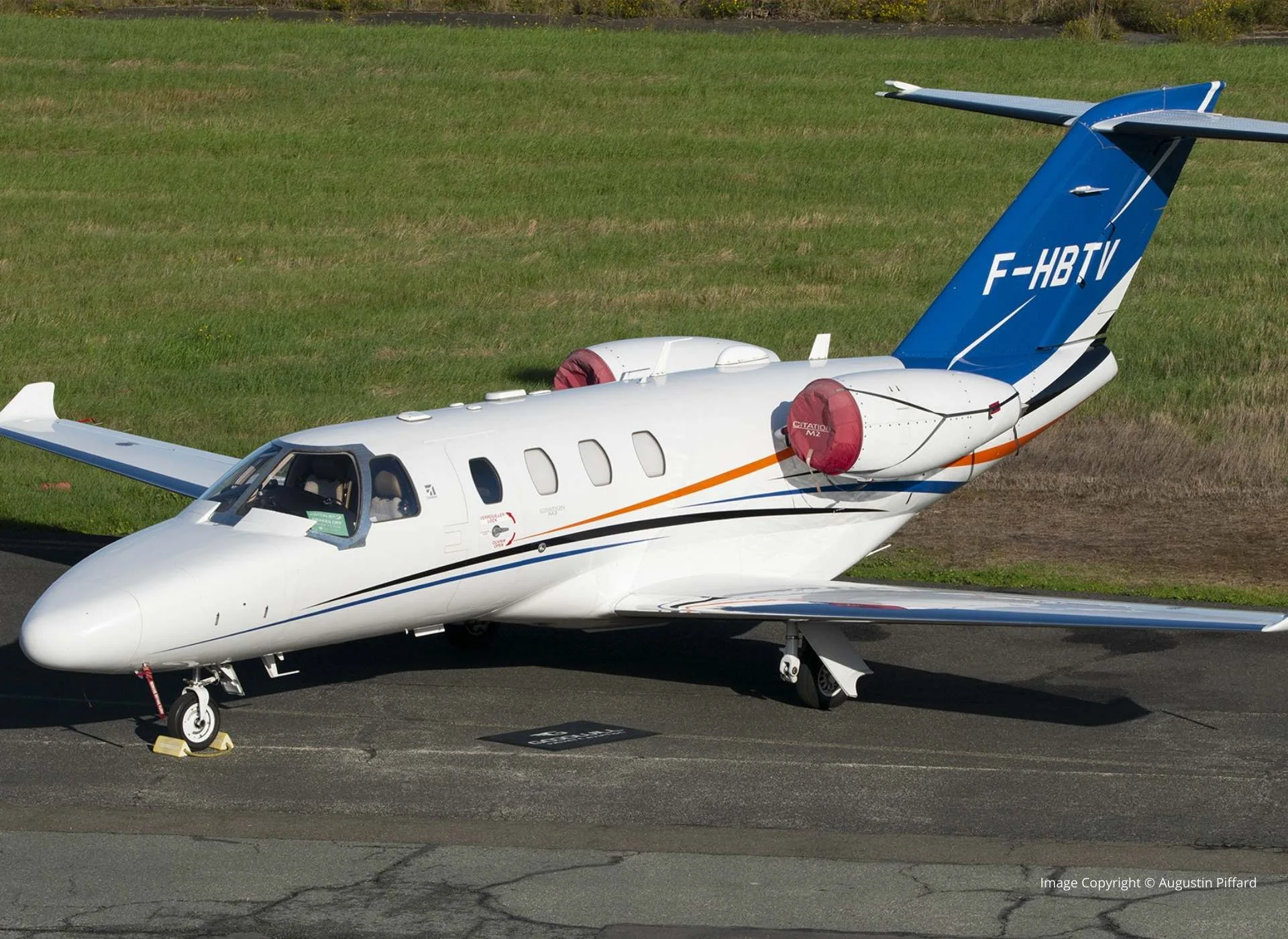 Jet privé Cessna Citation II stationné sur l’aire de trafic, vue latérale en biais, avec moteurs protégés et immatriculation visible.