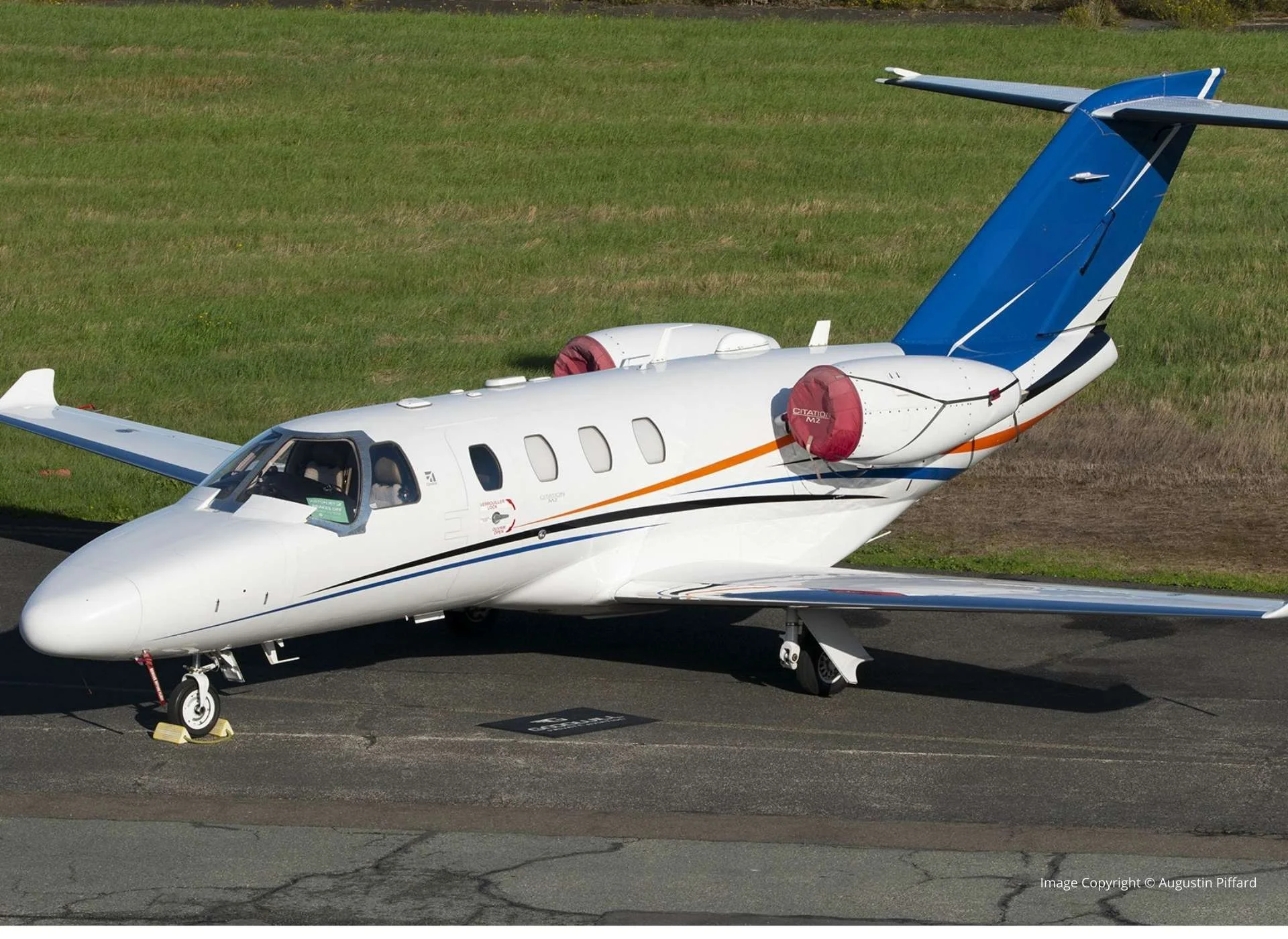 Cessna Citation II private jet parked on the apron, angled side view, with engines covered and tail registration visibl