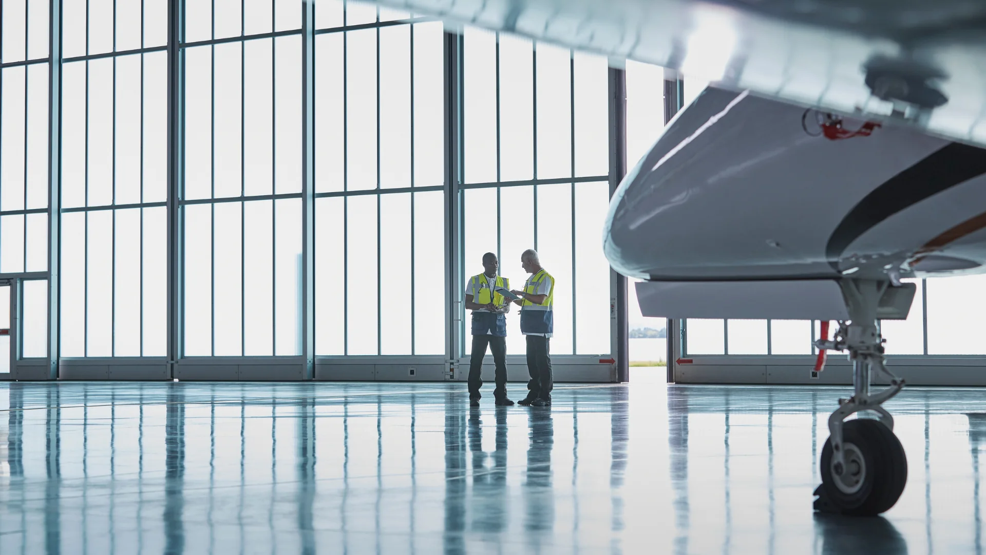 Private jet under maintenace in hangar with two mechanics