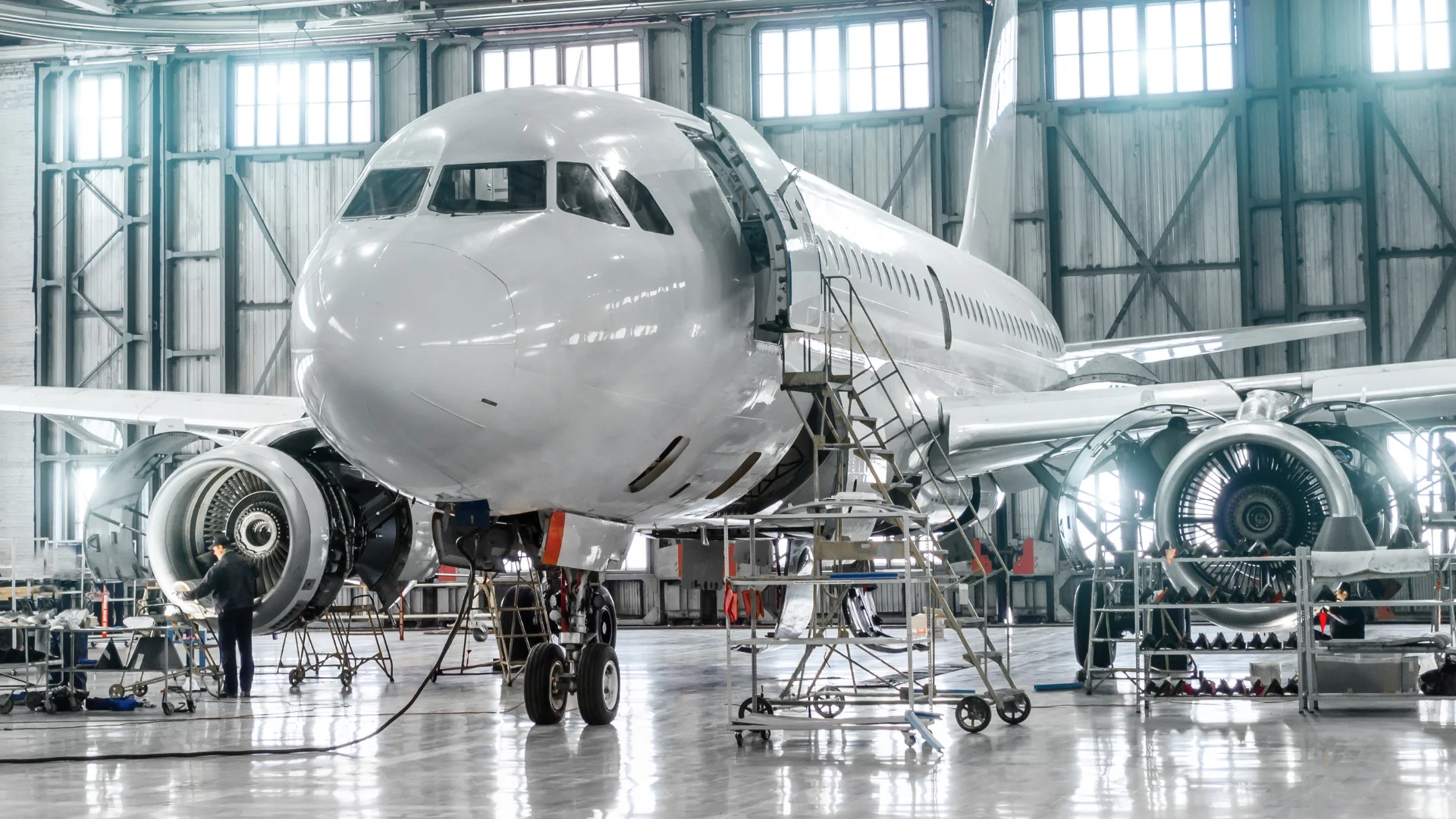 Technician performing maintenance on a commercial aircraft inside an aeronautical hangar