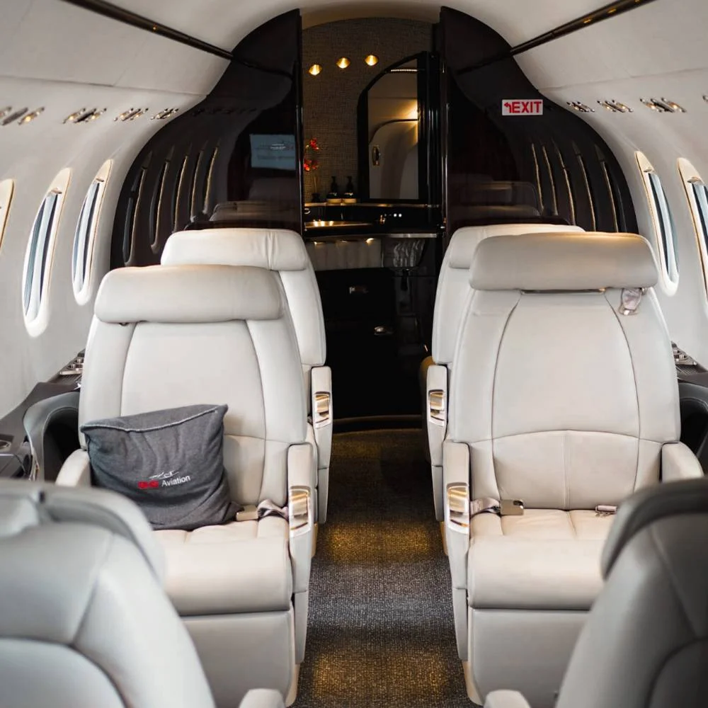 Private jet cabin interior with white leather seats and Artheau Aviation cushion