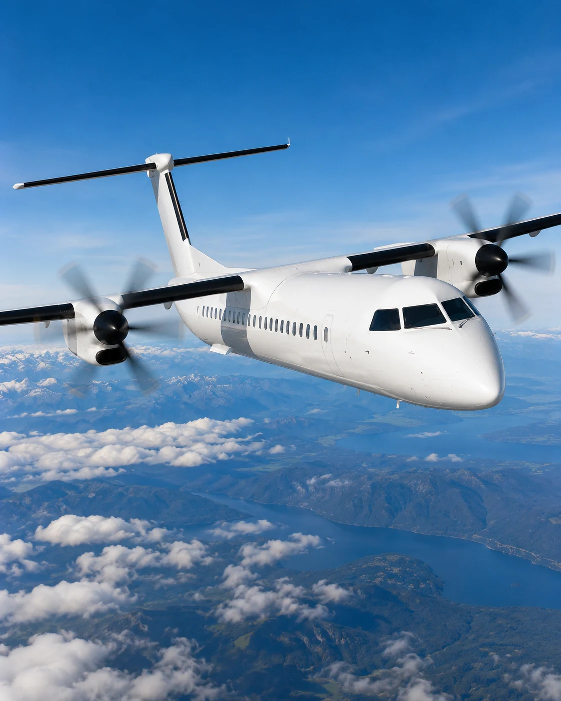 Front angle view of a Dash 8 Q400 aircraft in flight over mountains