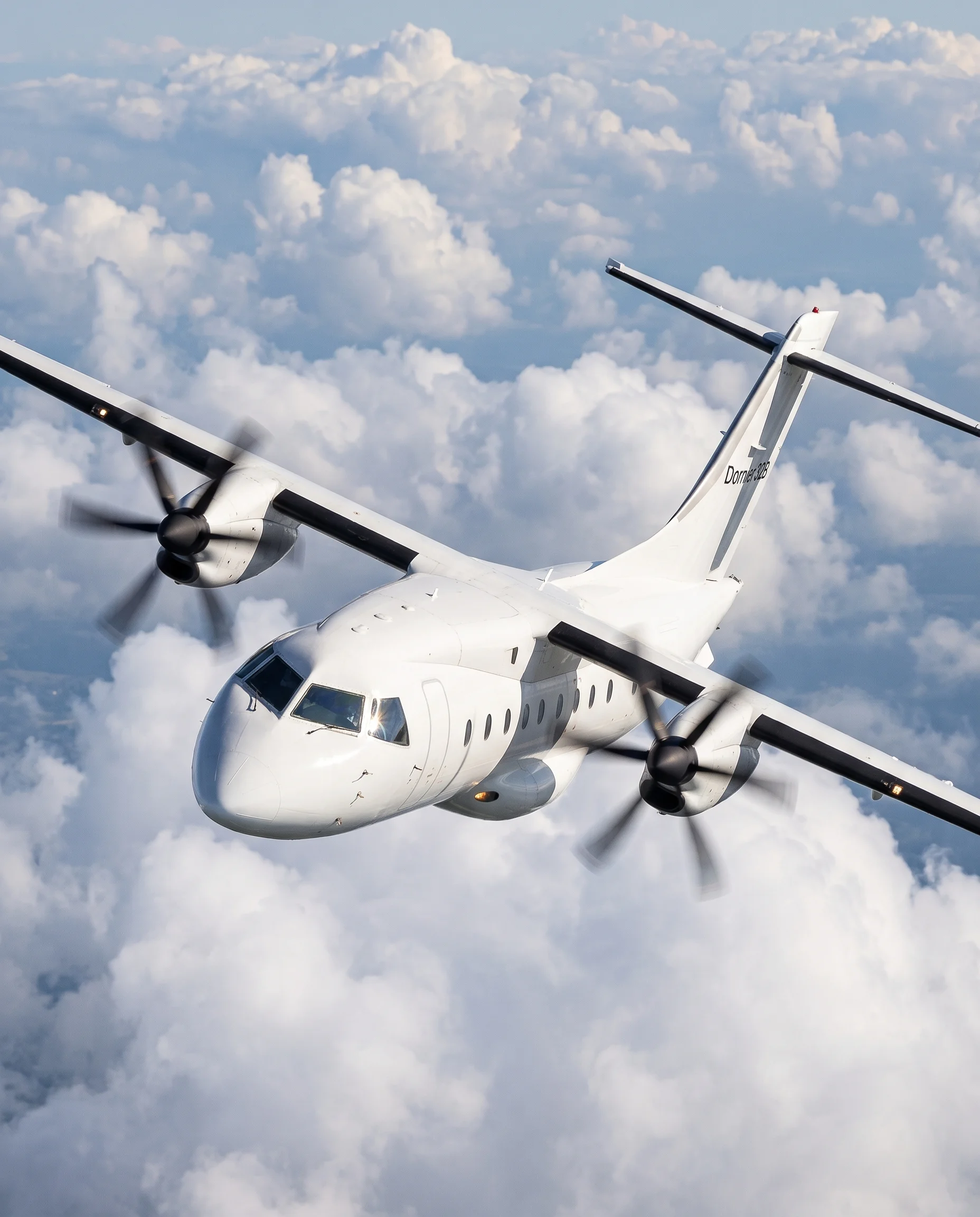 Front angle view of a Dornier 328 aircraft in flight above clouds