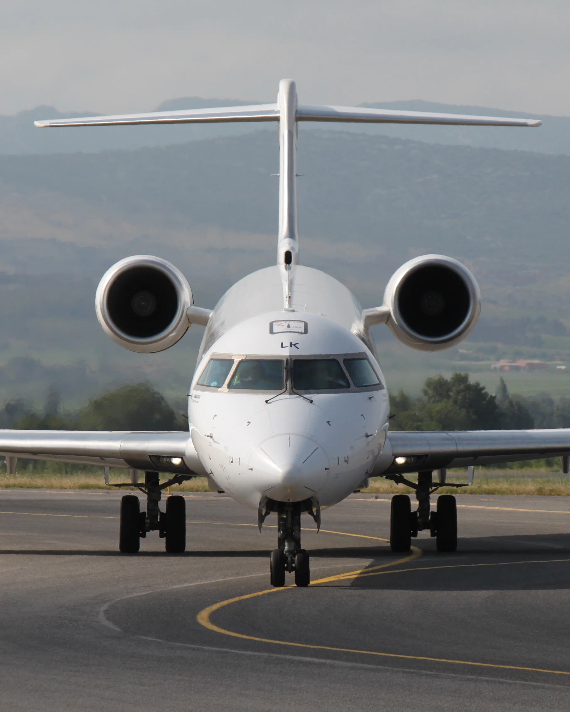 Front view of a CRJ1000 aircraft taxiing with mountains in the background