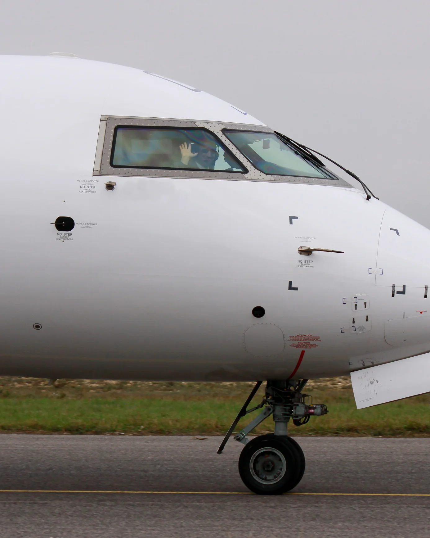 Close-up of a CRJ1000 aircraft nose showing the cockpit and emergency exit door
