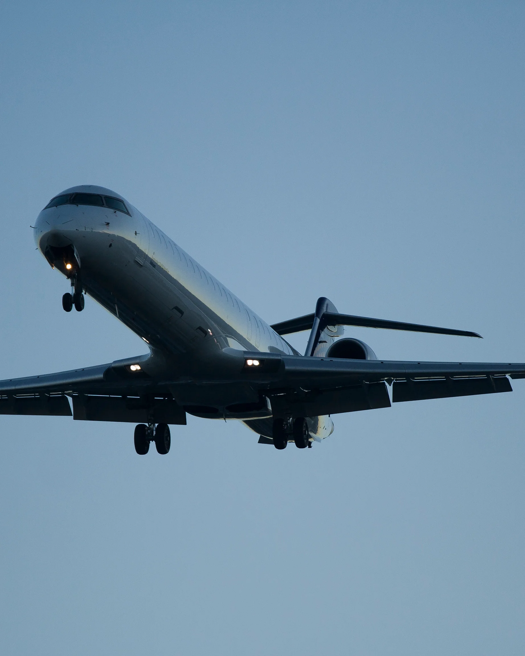 Side view of a CRJ1000 aircraft in flight at sunset