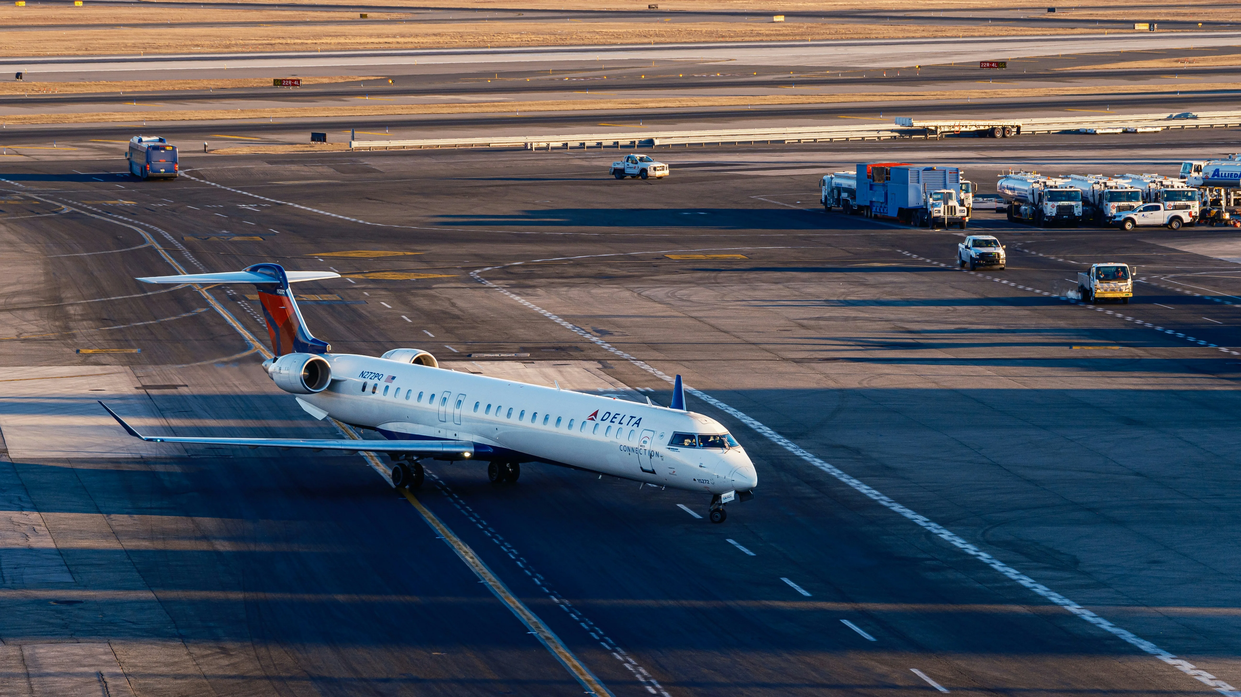 Aerial view of a Delta Connection CRJ900 aircraft taxiing among ground service vehicles
