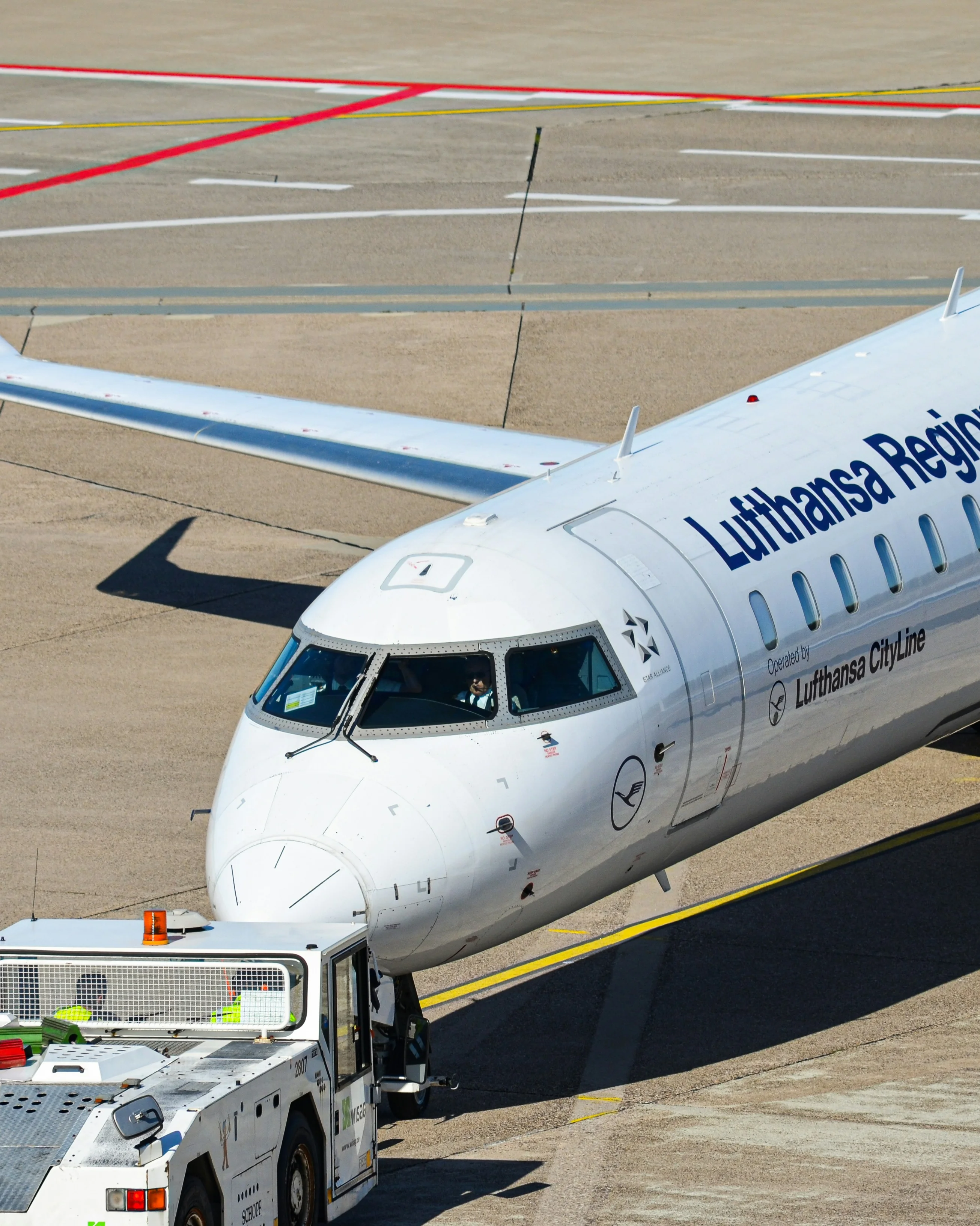 	Close-up of a Lufthansa Regional CRJ900 aircraft nose being towed on the apron