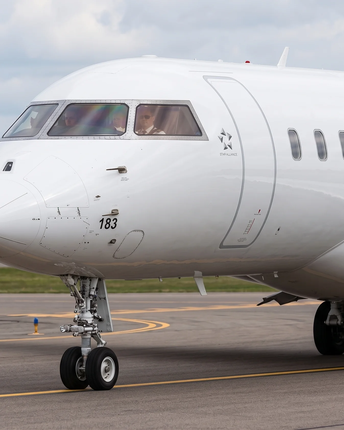 Close-up of a CRJ200 aircraft nose and cockpit on the taxiway with pilots visible
