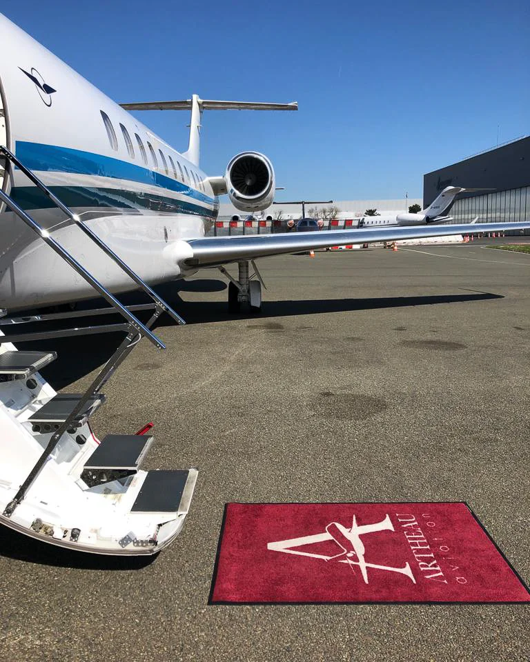 ERJ135 aircraft boarding stairs with an Artheau Aviation branded welcome mat on the apron