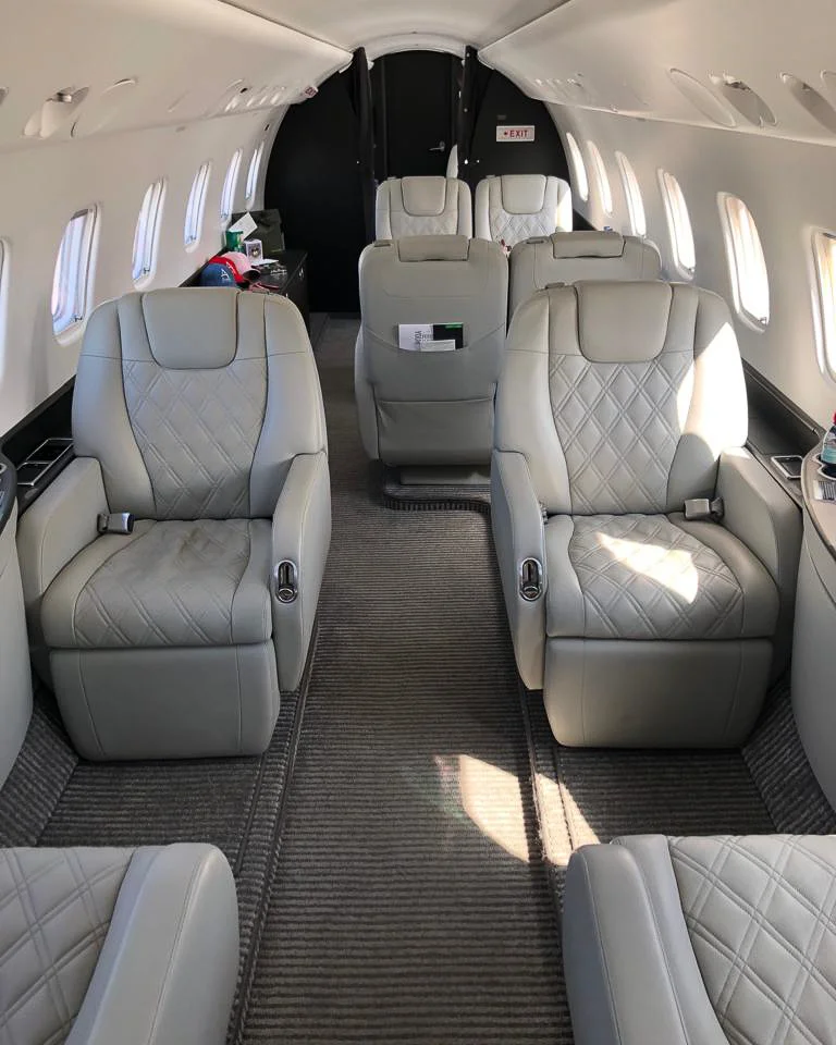 Interior of an ERJ135 aircraft cabin showing rows of leather seats