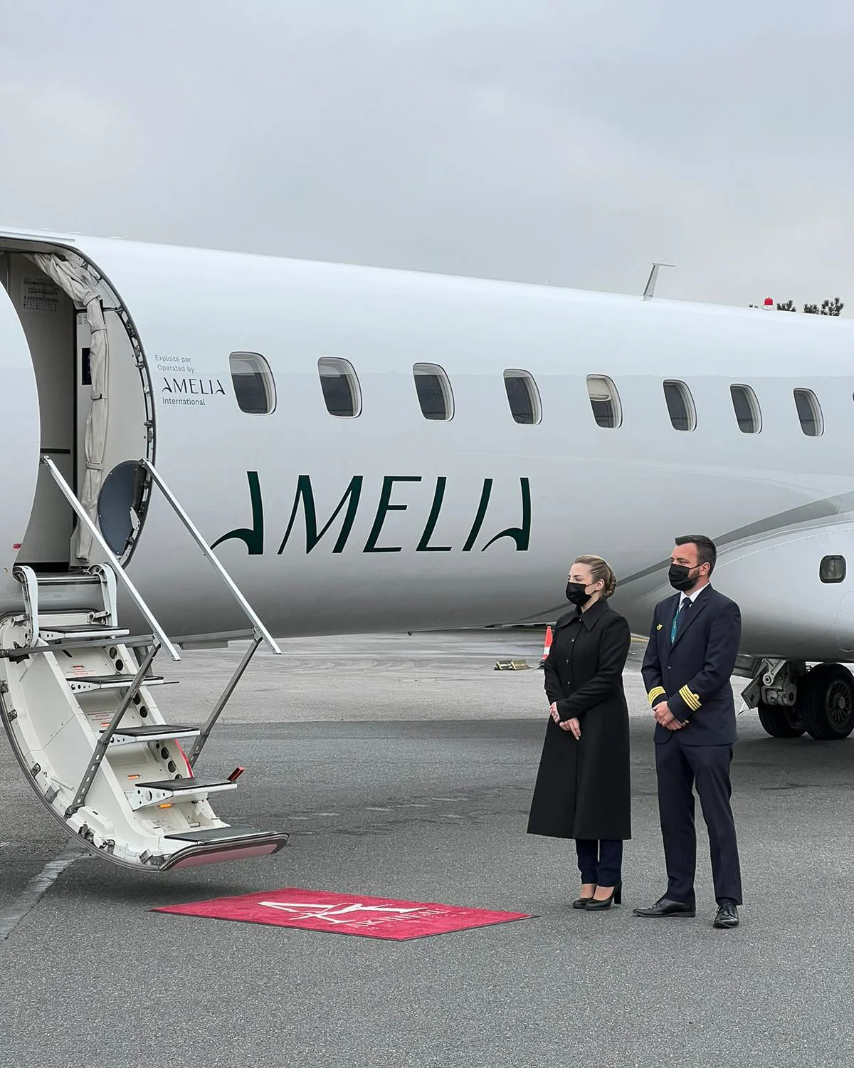 ERJ145 aircraft operated by Amelia International with crew standing beside the boarding stairs