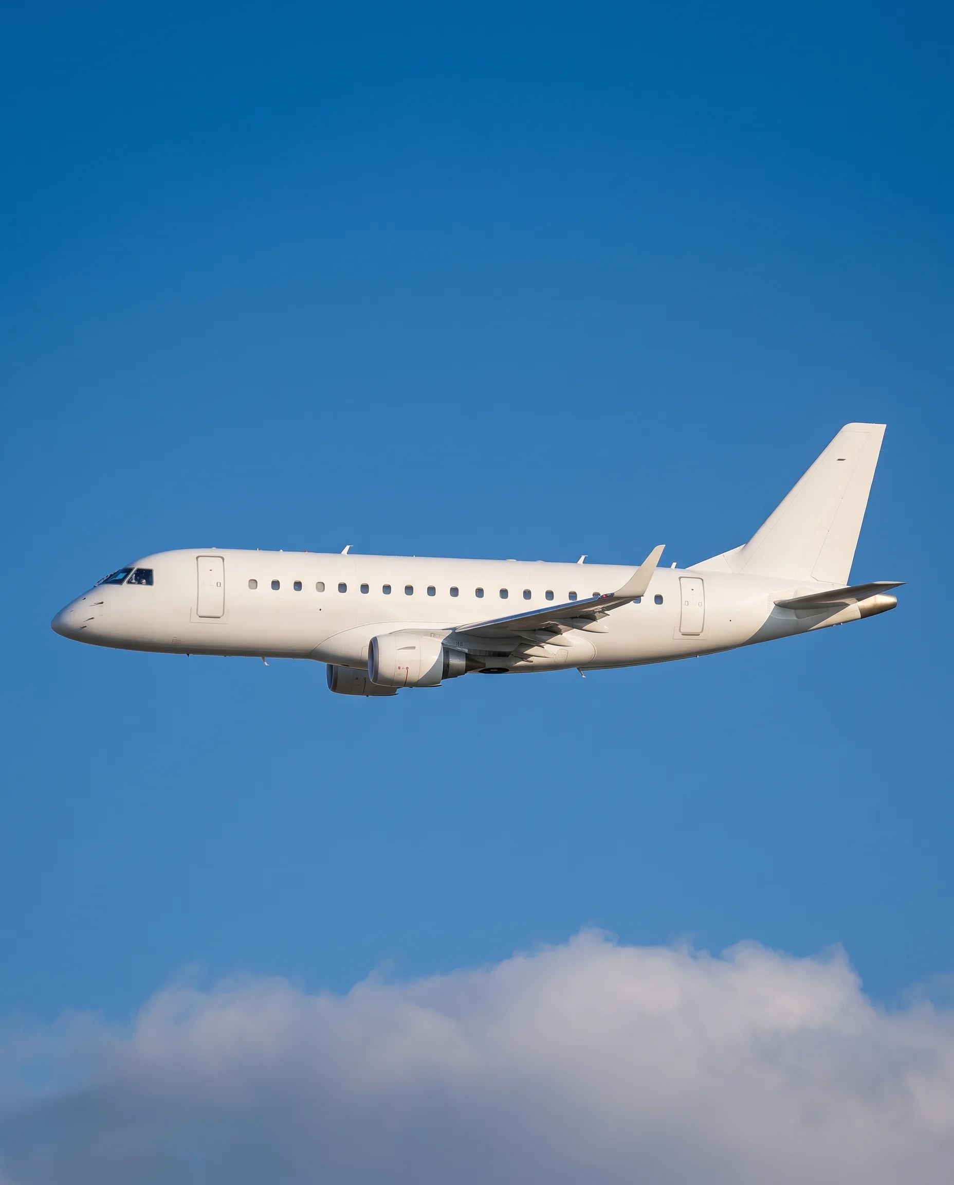 Embraer ERJ170 aircraft climbing above clouds with its reflection visible below