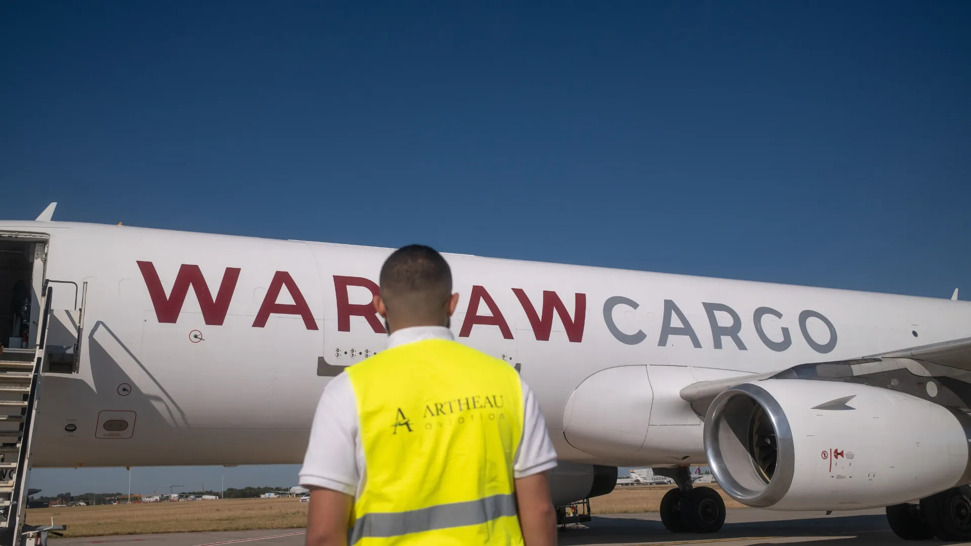 Agent Artheau Aviation en gilet de sécurité face à un avion cargo sur le tarmac, avant le chargement du fret aérien