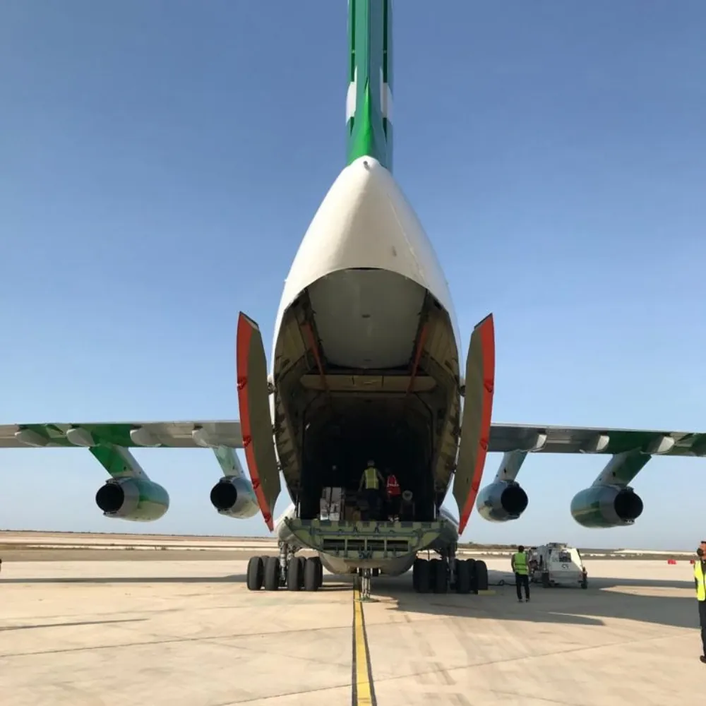 Gros-porteur cargo stationné sur le tarmac, soute arrière ouverte pendant le chargement du fret par l'équipe au sol