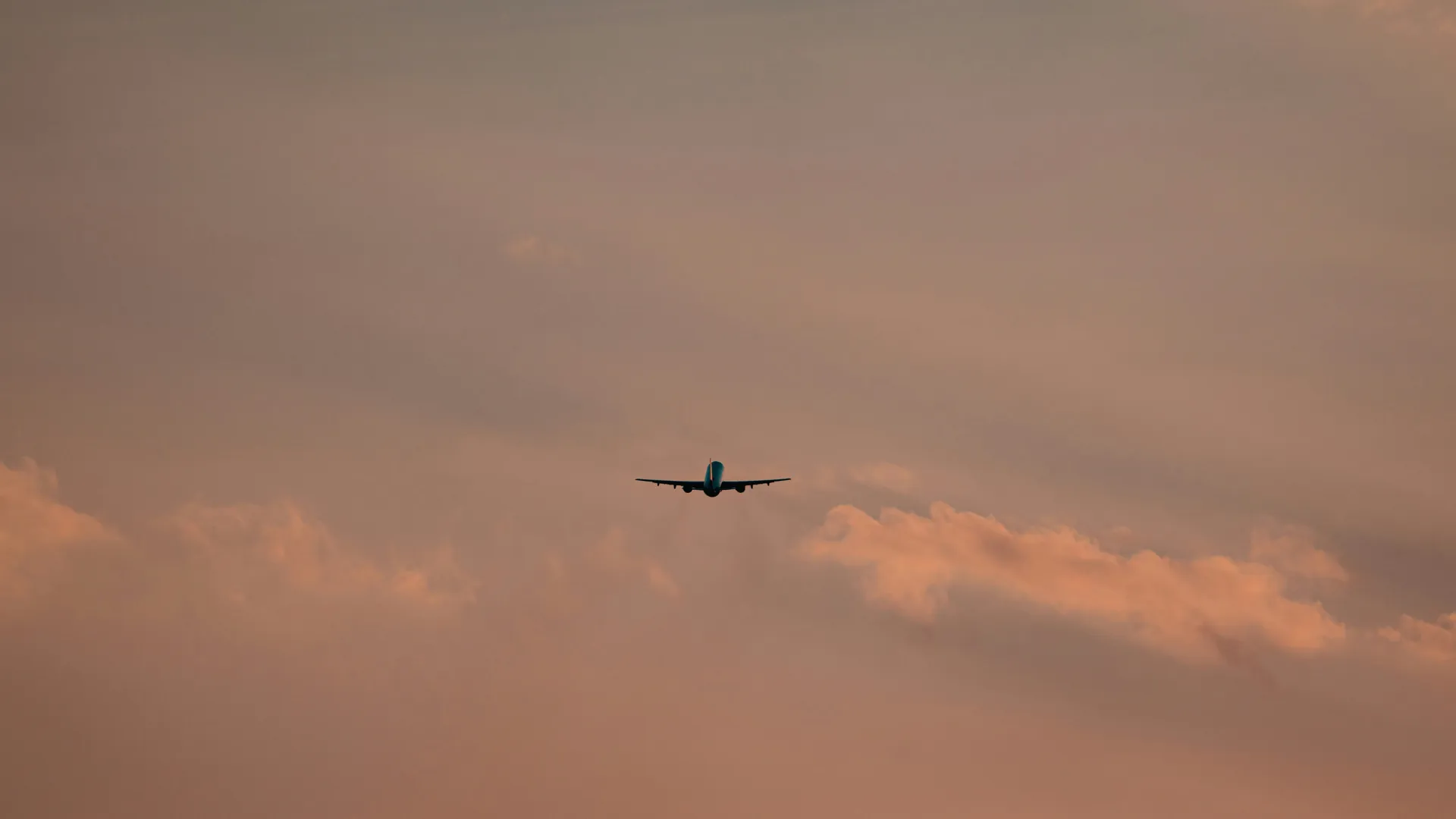 Avion en montée après le décollage dans un ciel rosé au coucher du soleil