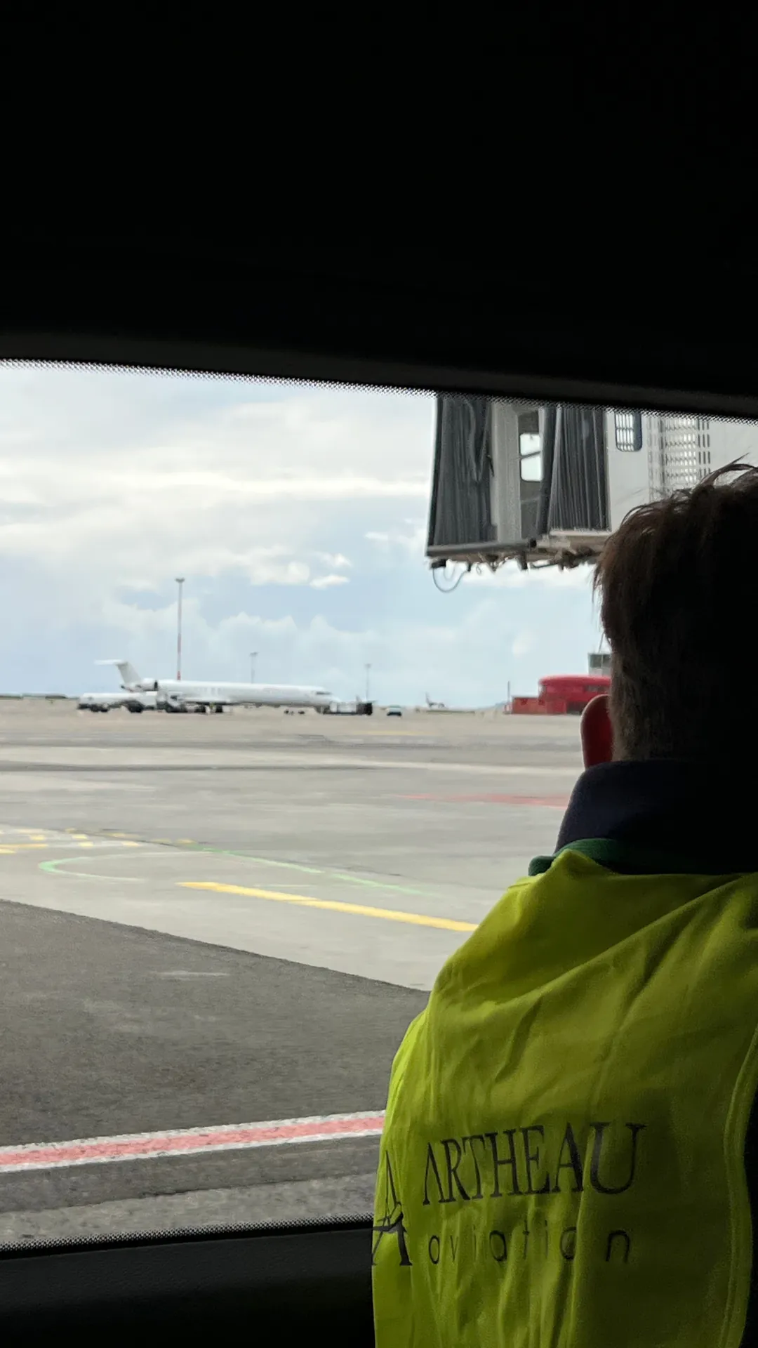 Courtier aérien Artheau Aviation en gilet de sécurité observant un avion stationné sur le tarmac depuis un véhicule d'assistance
