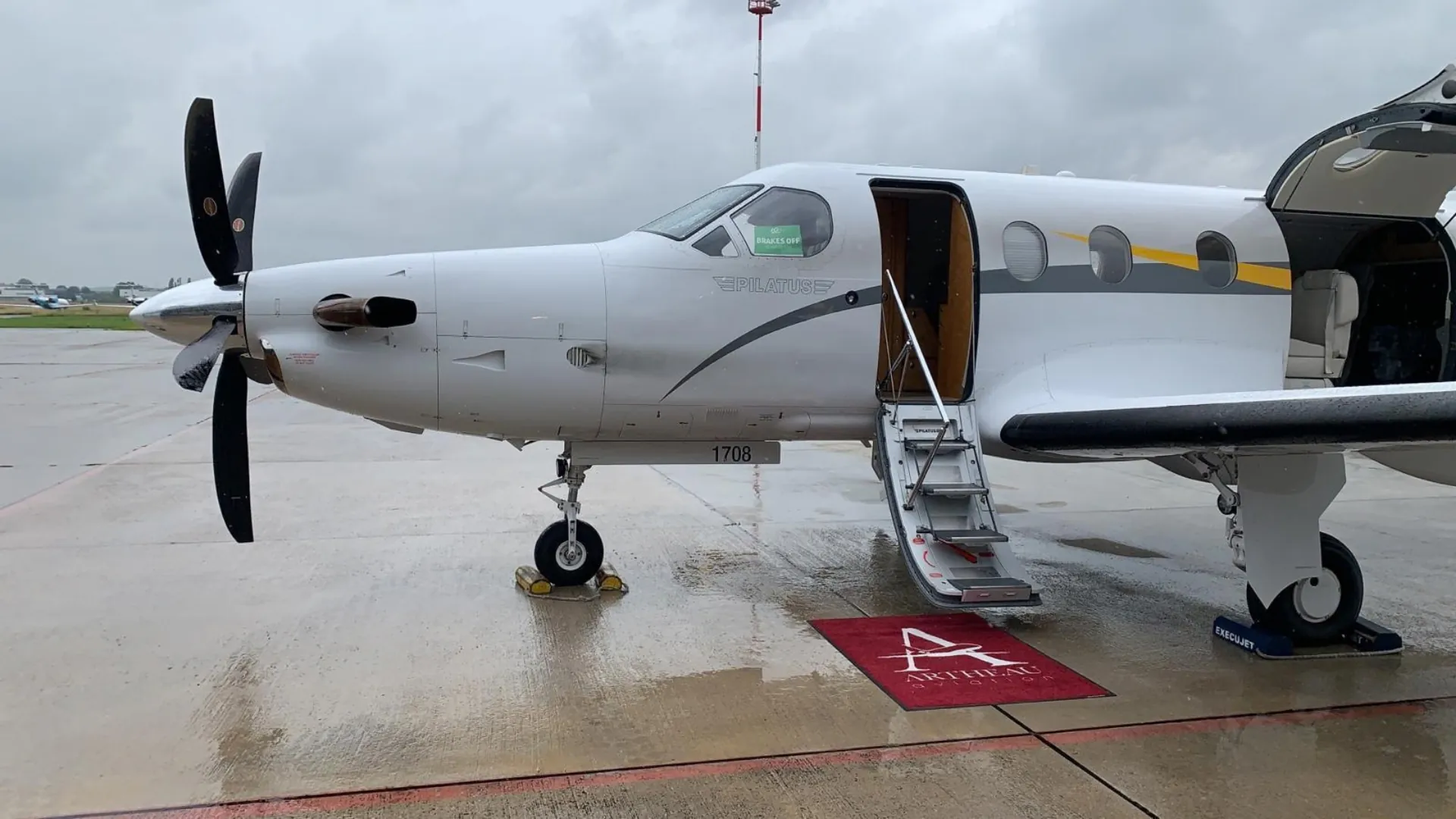 Avion Pilatus PC-12 porte ouverte sur le tarmac, avec un tapis rouge Artheau Aviation au pied de l'escalier