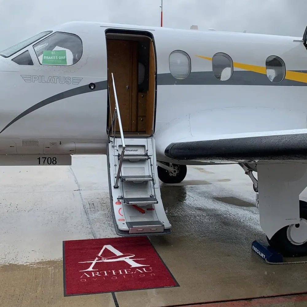 Escalier d'embarquement déployé d'un Pilatus PC-12, avec un tapis rouge Artheau Aviation posé au sol