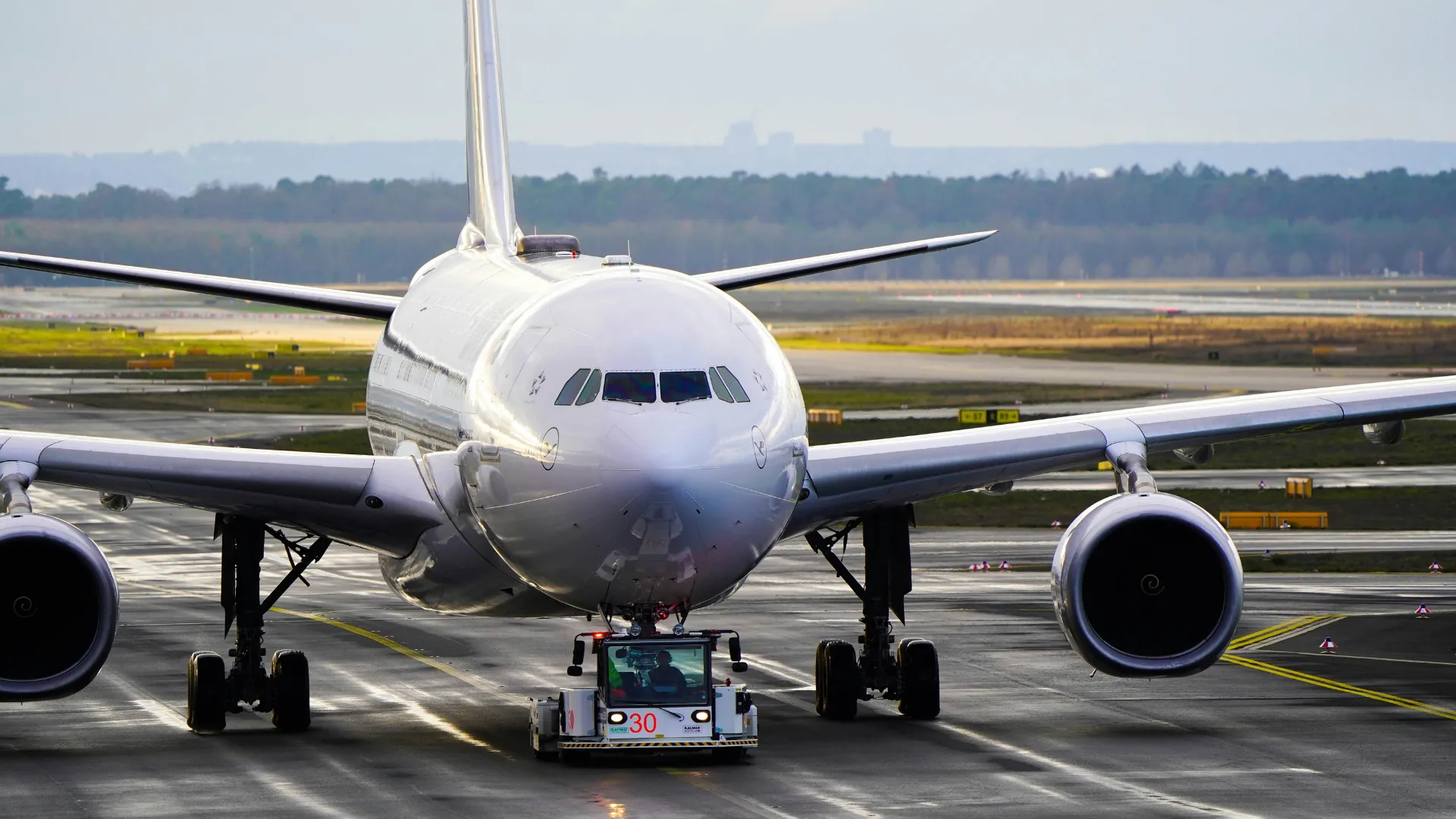 Avion long-courrier vu de face, remorqué par un tracteur de piste sur le tarmac d'un aéroport
