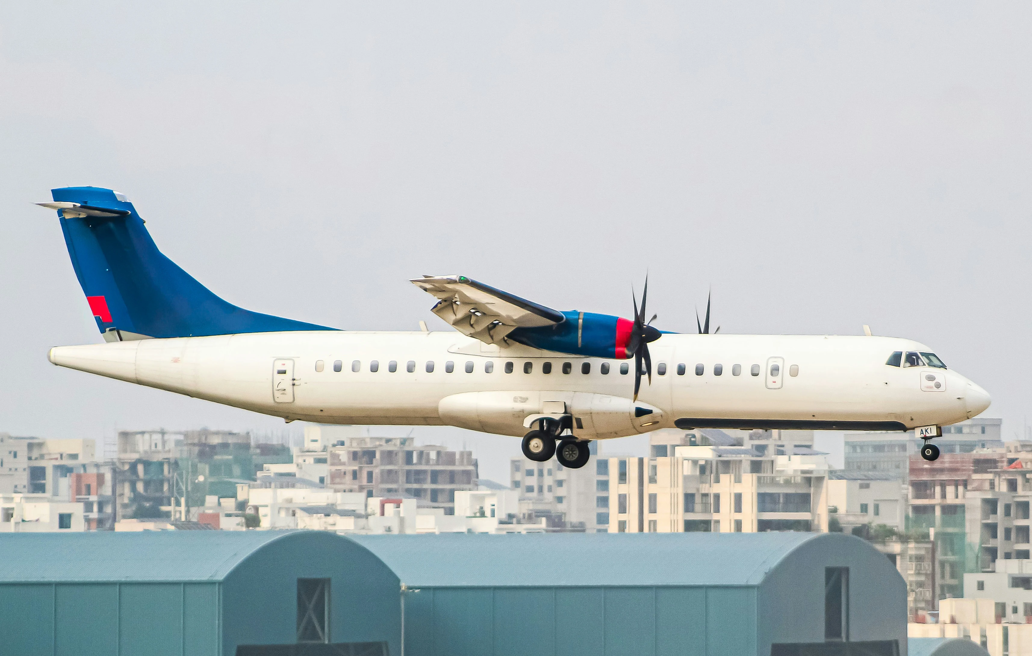 ATR 72 turboprop aircraft on final approach with a city skyline