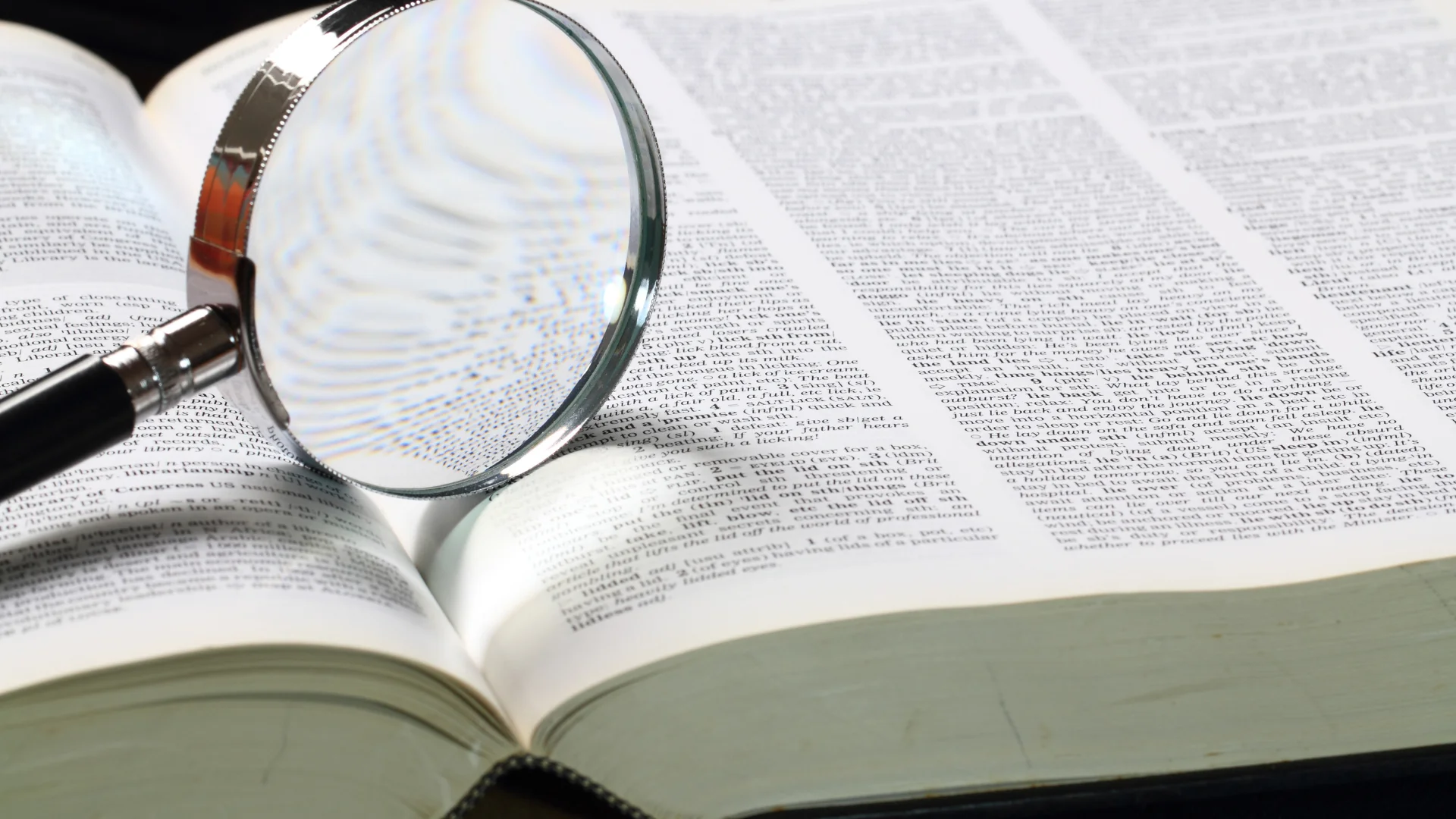 Open dictionary and magnifying glass