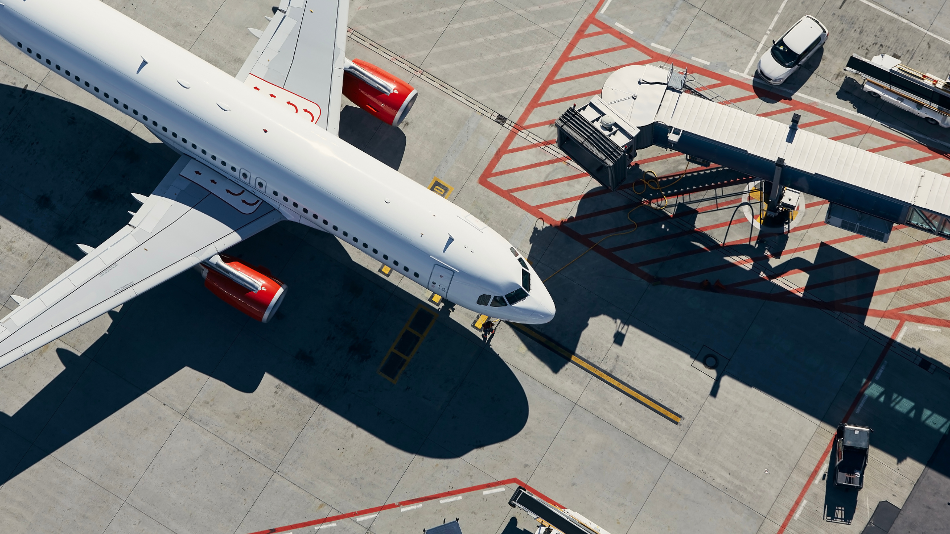 Aerial view of a passenger aircraft at its stand with ground vehicles