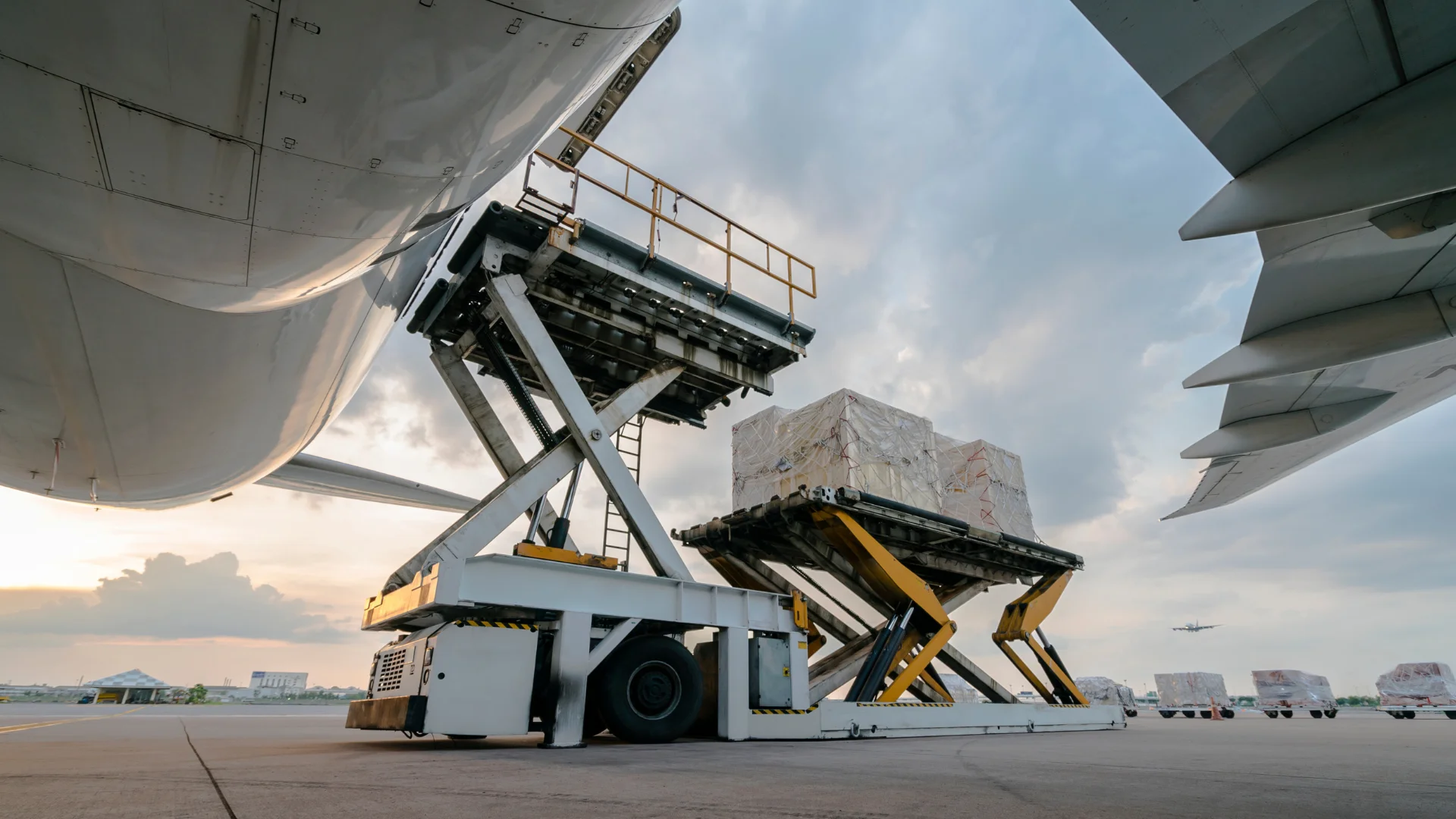 Cargo loader lifting pallets to an aircraft