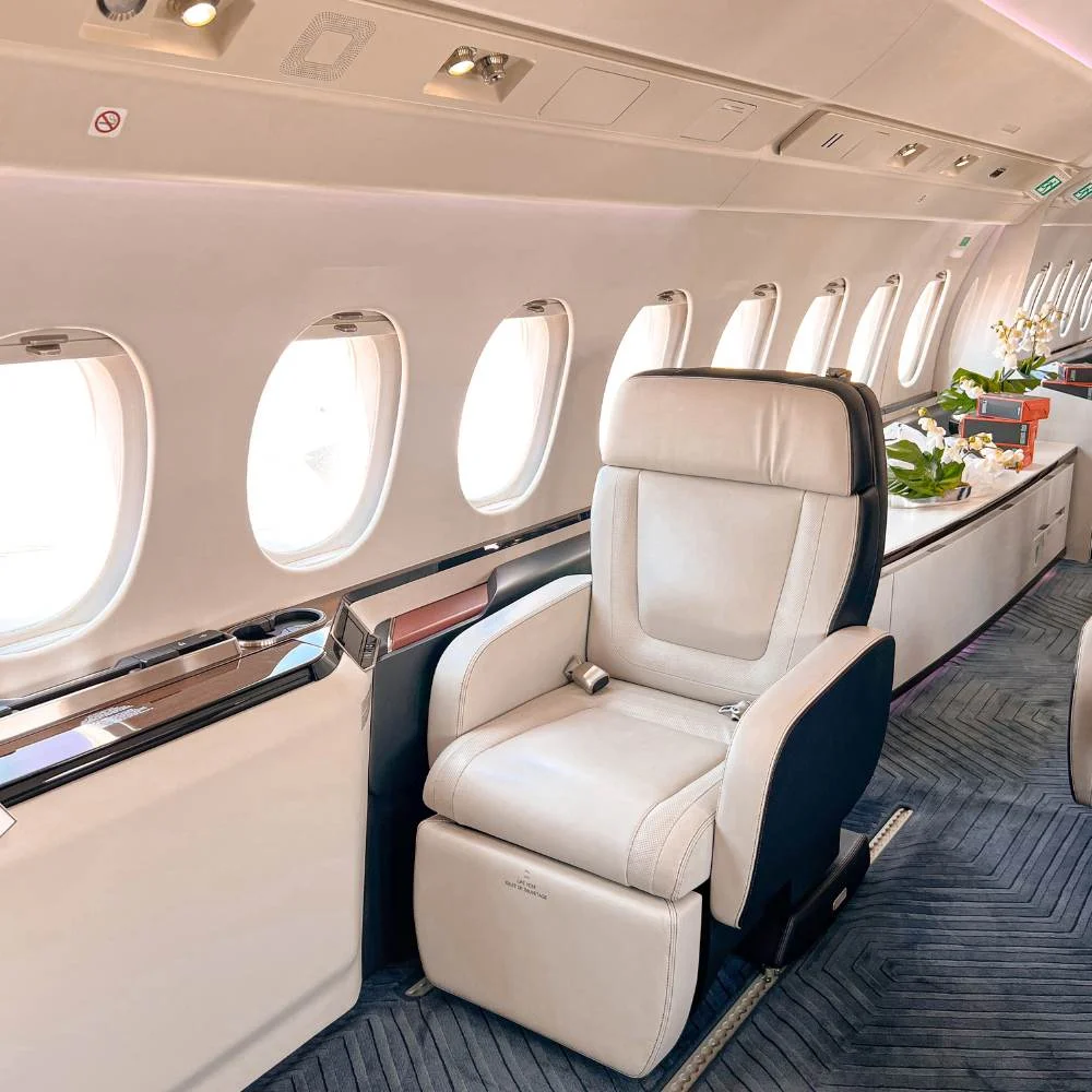Private jet cabin with a cream leather seat and side credenza