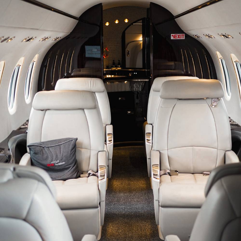 Private jet cabin with cream leather seats and an Artheau Aviation cushion