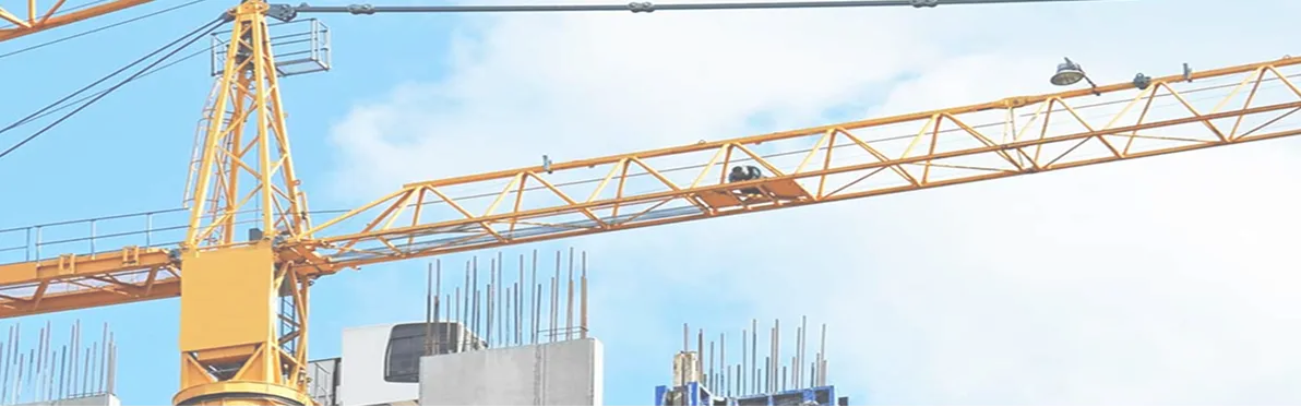 Yellow construction crane lifting materials at a building site against a partly cloudy blue sky.