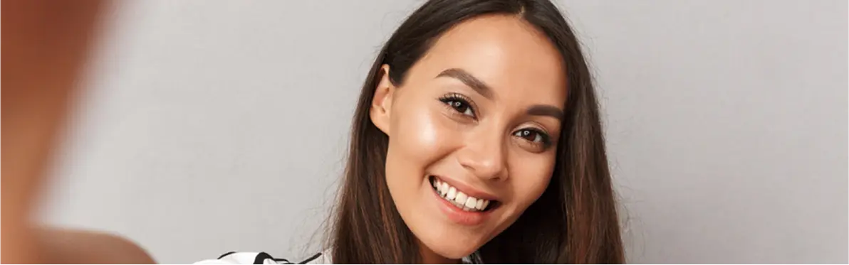 Smiling young woman with long brown hair and natural makeup looking at the camera.